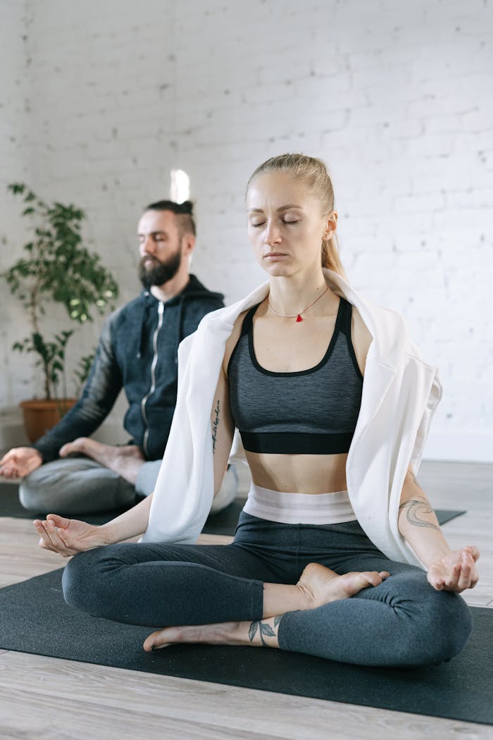 Two adults meditating in a tranquil indoor setting, promoting wellness and focus.